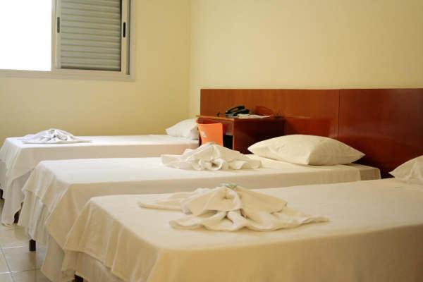 duas camas num quarto de hotel com toalhas em Hotel Morada do Sol em Araxá