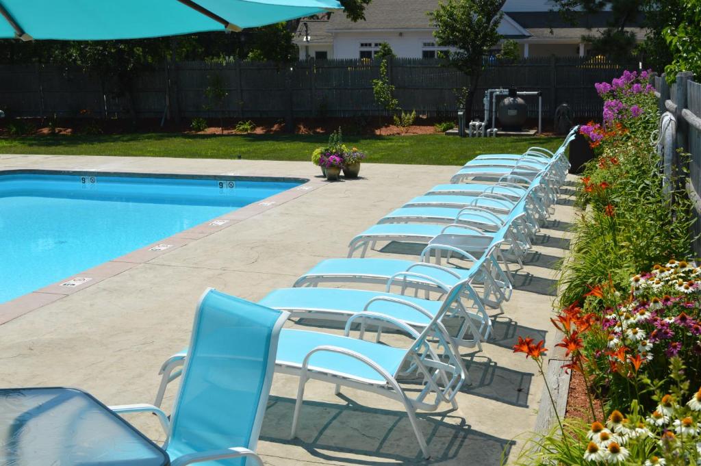 a row of blue chairs next to a swimming pool at The Escape Inn in South Yarmouth