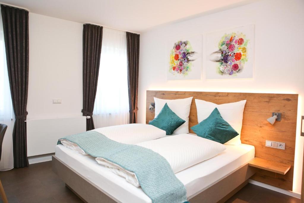 ein Schlafzimmer mit einem weißen Bett und grünen Kissen in der Unterkunft Gasthof Adler Inneringen in Inneringen-Hettingen