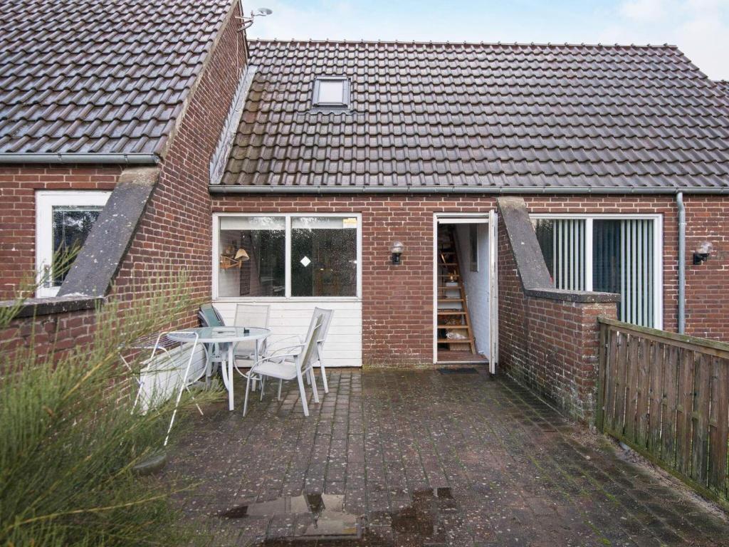 ein Backsteinhaus mit einer Terrasse mit einem Tisch und Stühlen in der Unterkunft Holiday Home Lyngvejen IV in Rømø Kirkeby