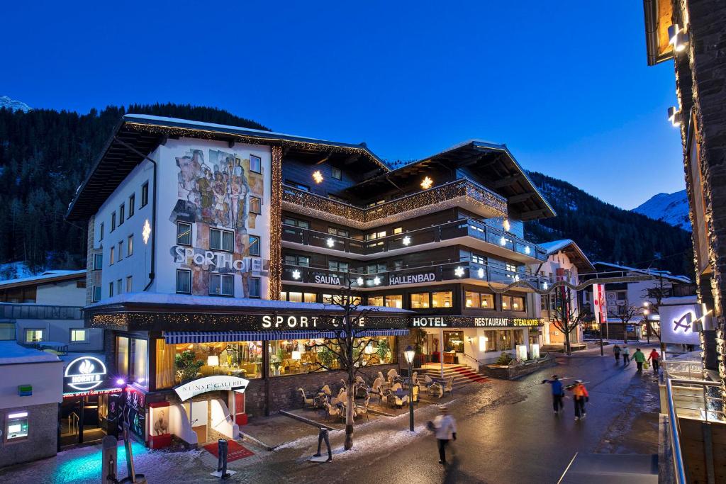 a large building with people walking in front of it at Sporthotel St. Anton in Sankt Anton am Arlberg