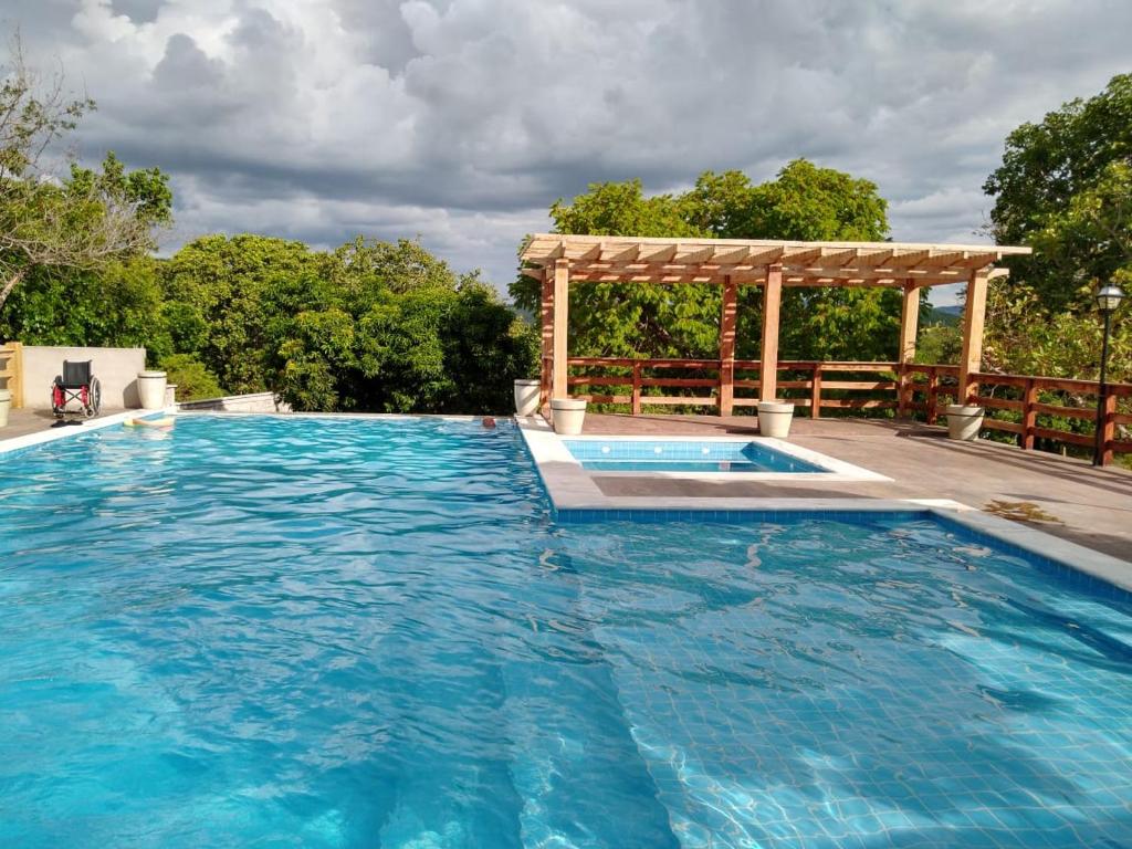 a large swimming pool with a wooden pergola and a swimming pool at Pousada Portalcion in Goiás
