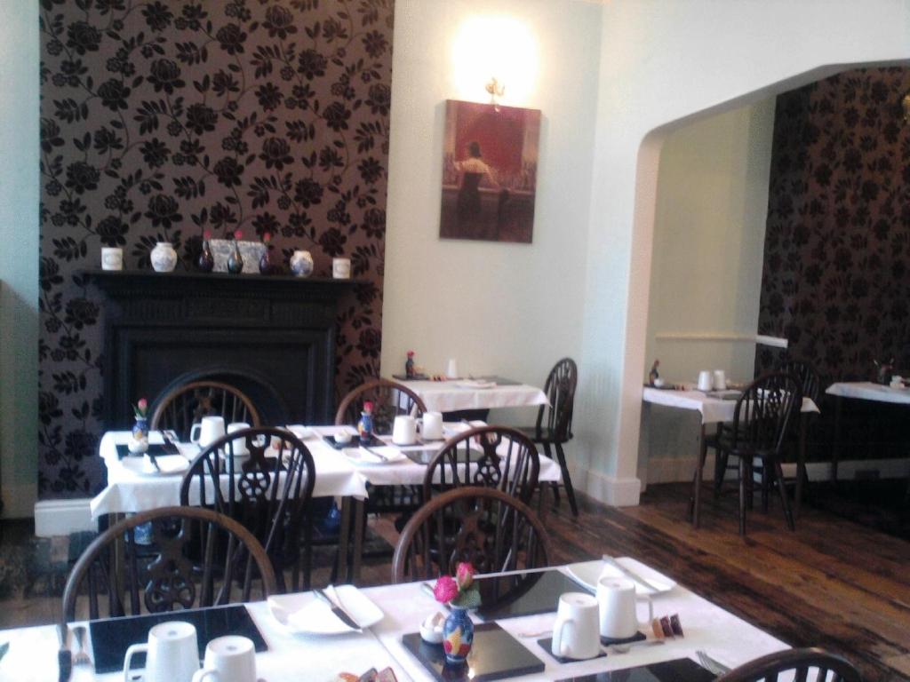 a dining room with tables and chairs and a fireplace at Seahaven House in Ryde