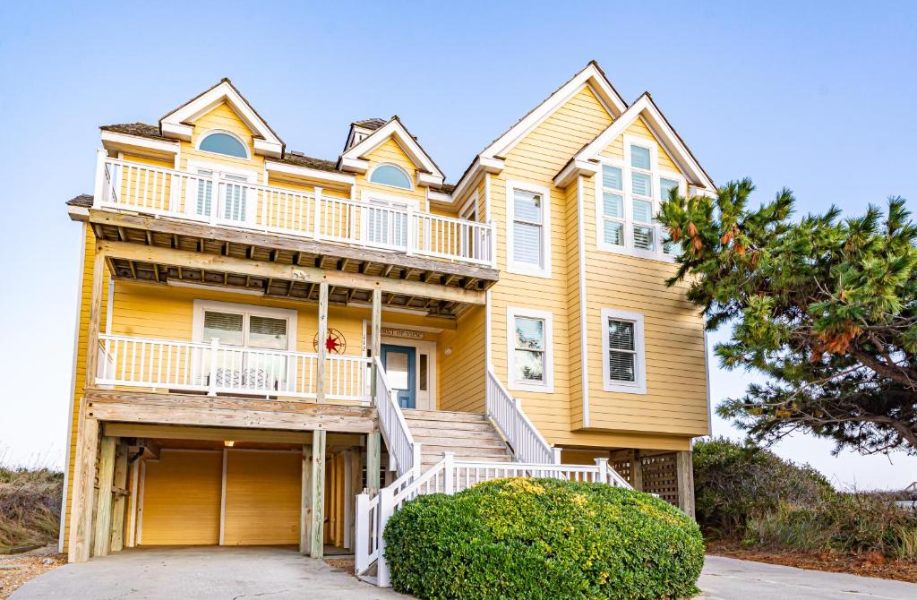 a yellow house with a porch and stairs at Point of View in Nags Head