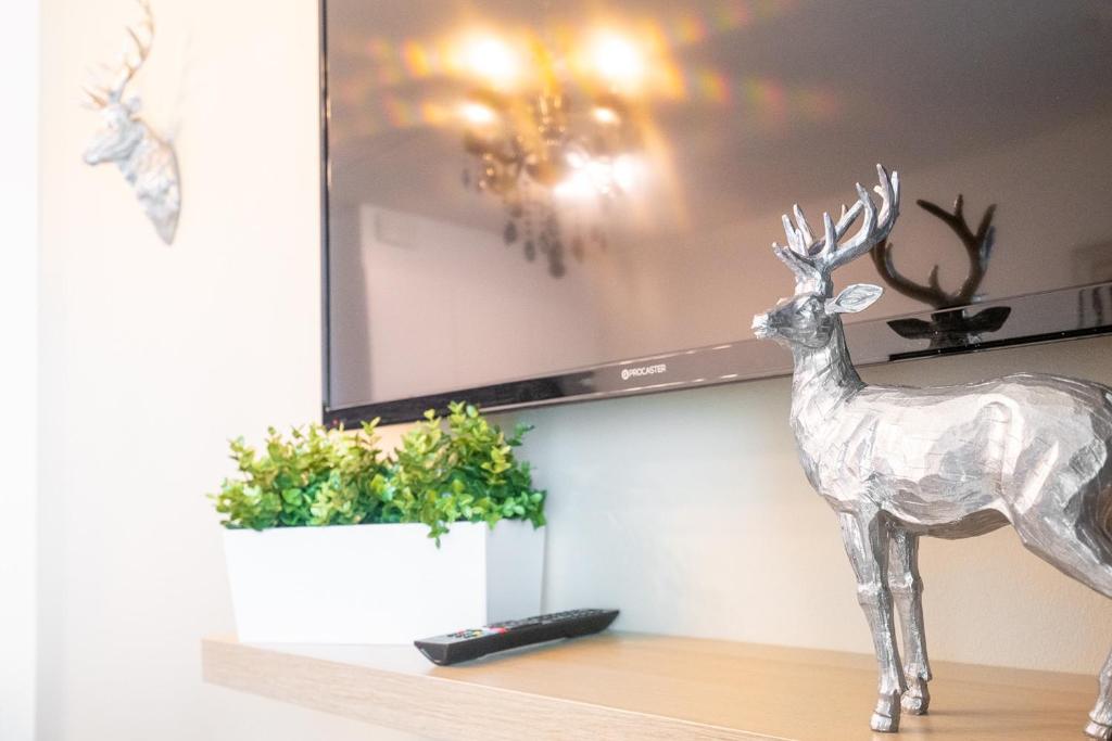 a statue of a deer on a shelf with a tv at Trendy Homes Oulu Apartments in Oulu