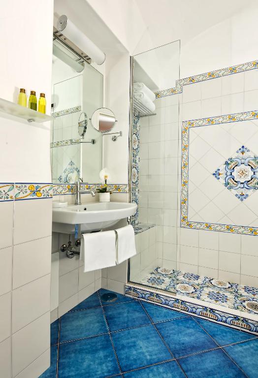 un bagno con lavandino e specchio di Albergo Gatto Bianco a Capri