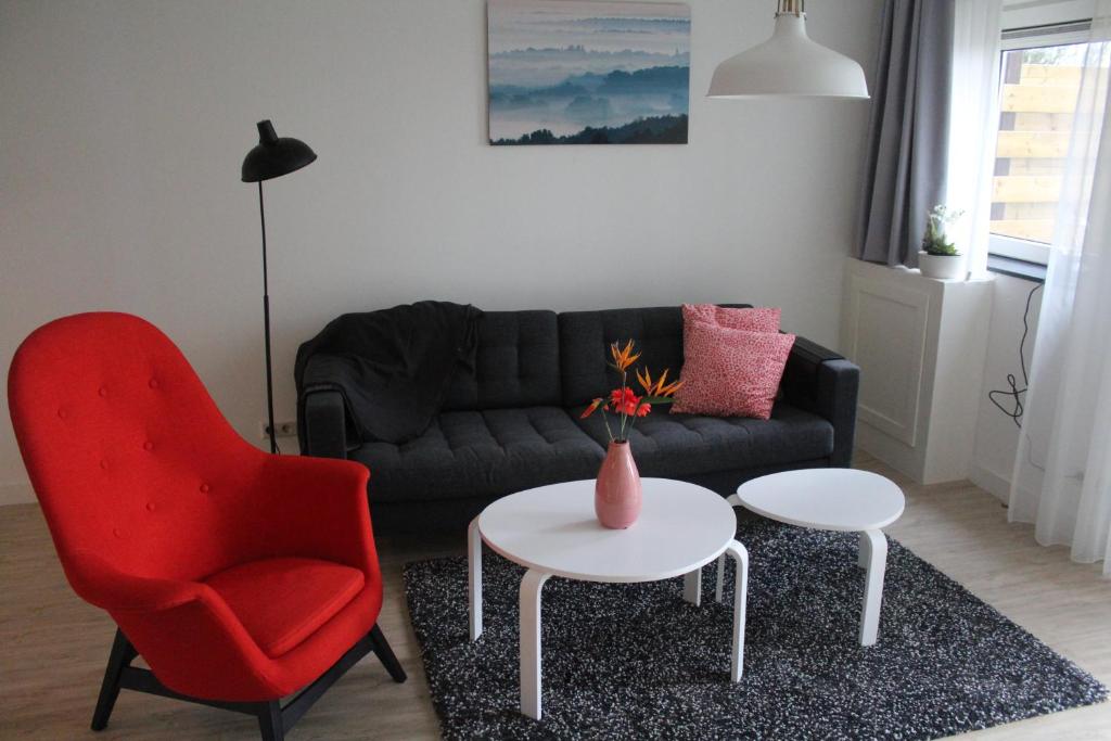 Sala de estar con sofá, silla roja y mesa en Veldhuis, en Woubrugge