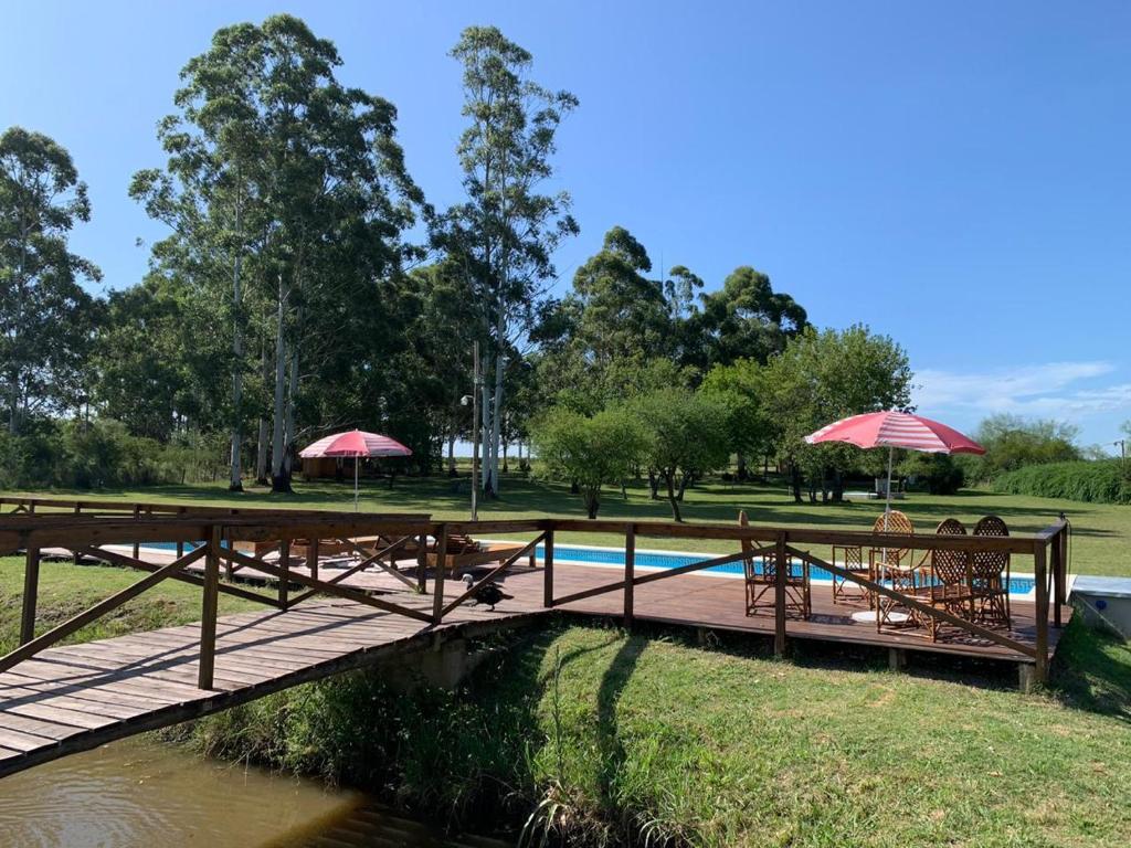 un ponte di legno con tavoli e ombrelloni accanto a una piscina di Posada Los Molles a Colón