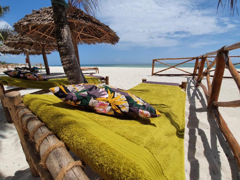 a bed on the beach with an umbrella at MOYO apartment in Pwani Mchangani