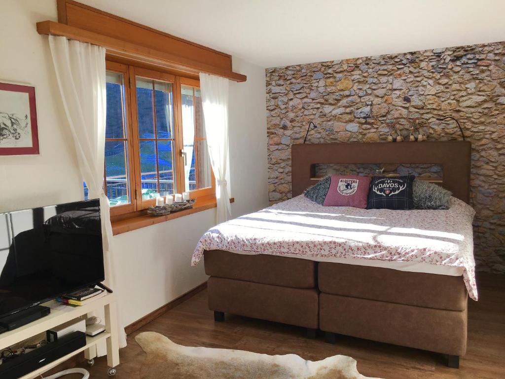 1 dormitorio con cama y pared de piedra en Apartment Allegra en Küblis