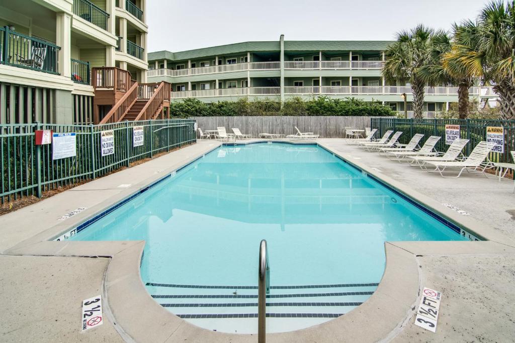 une grande piscine avec des chaises et un bâtiment dans l'établissement Ocean Boulevard Villas 101, à Isle of Palms