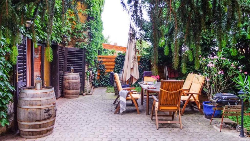 un patio al aire libre con mesa, sillas y barriles en Kamocsay Vendégház, en Mór