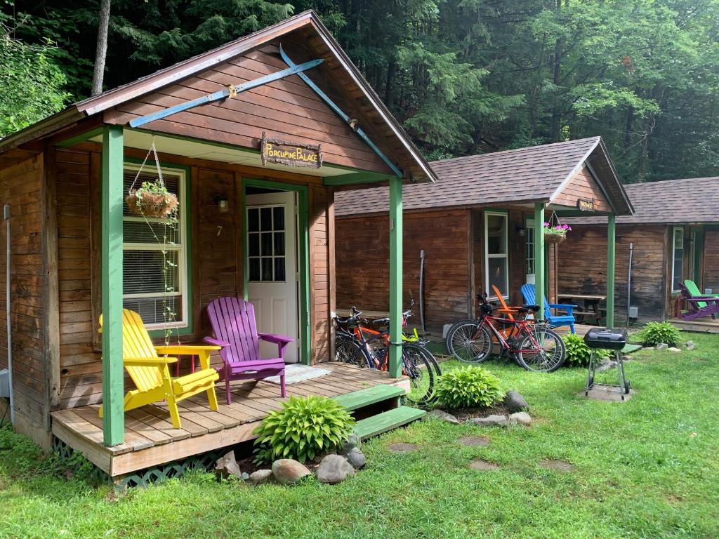 Cabaña de madera con 2 sillas en una terraza en Pine Crest Motel & Cabins en Barton