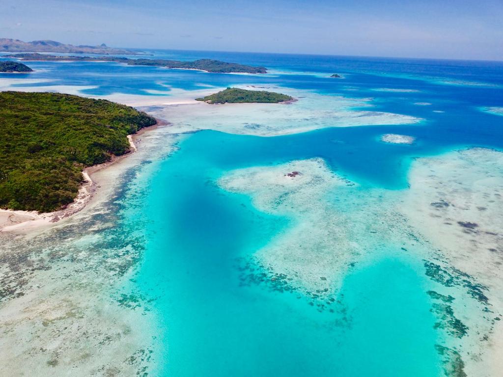 une île dans l'océan avec des eaux bleues et des récifs dans l'établissement Long Beach Escape, à Vuake