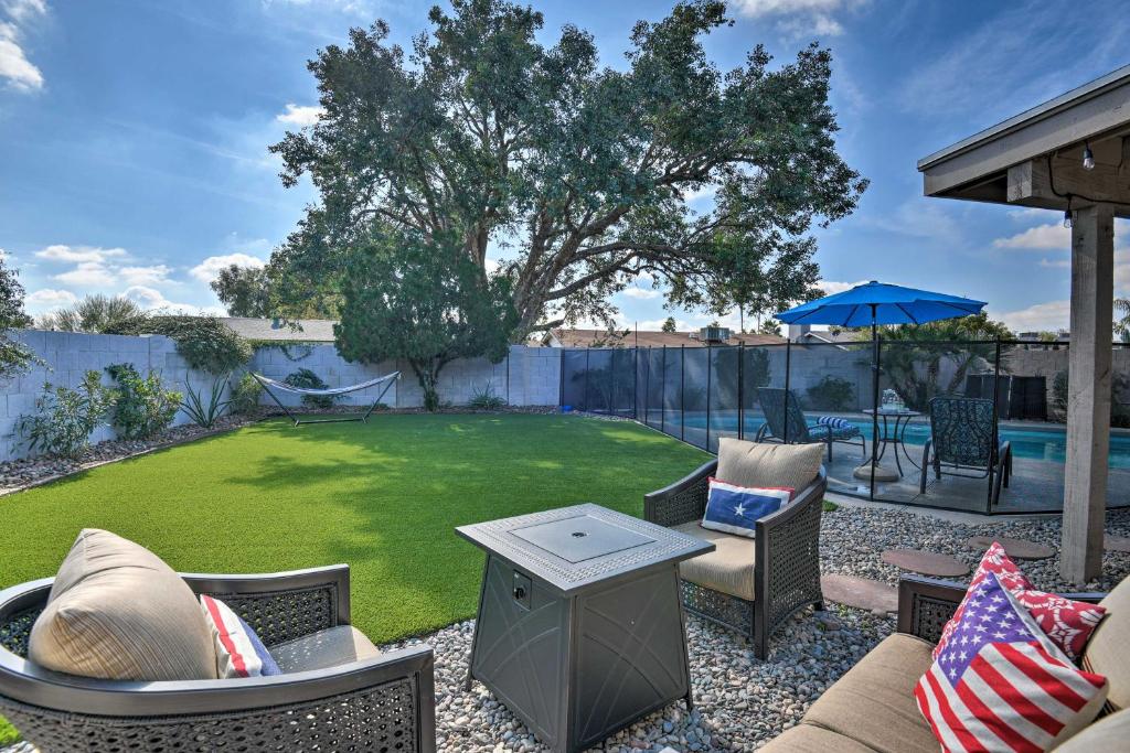 a patio with chairs and a yard with a pool at Scottsdale Home with Pool, Yard, Hammock and Fire Pit! in Scottsdale