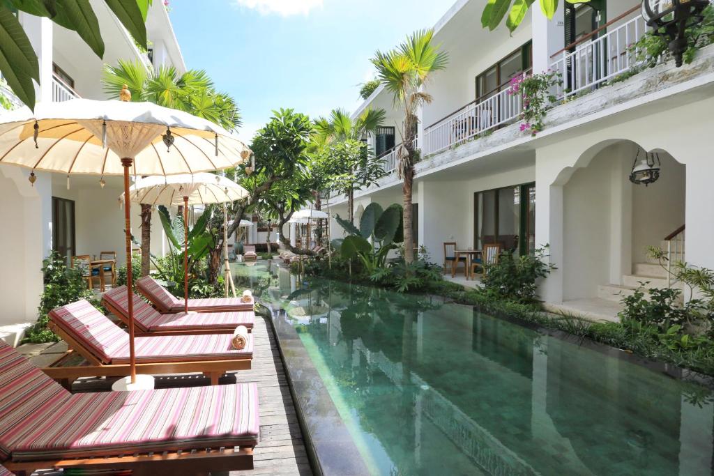 
a patio area with a pool, chairs, and a patio umbrella at Sabana Ubud in Ubud
