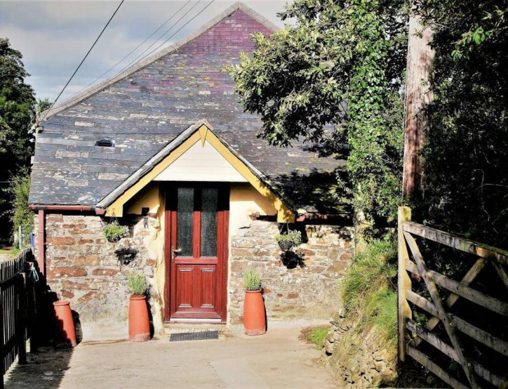 mały kamienny dom z czerwonymi drzwiami w obiekcie Cottage Barn, Jacobstow w mieście Bude