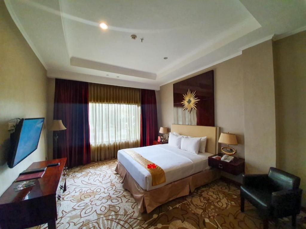 a hotel room with a large bed and a desk at Sutanraja Hotel & Convention Centre in Soreang