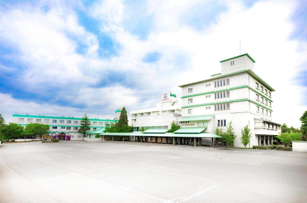 Hirakawa的住宿－津輕之宿 南田溫泉 蘋果園飯店，一座大型白色建筑,设有停车场