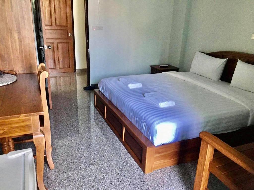 a bedroom with a bed and a table and a desk at โรงแรมคูณคีม in Nakhon Phanom