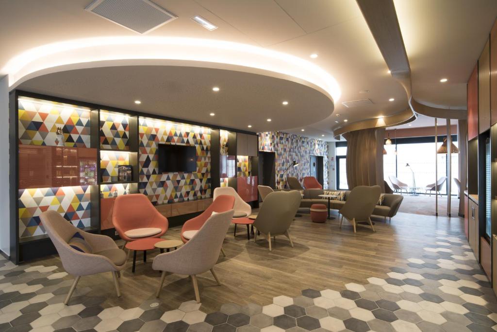 a waiting room with chairs and tables in a building at Holiday Inn Express - Paris - CDG Airport by IHG in Roissy-en-France