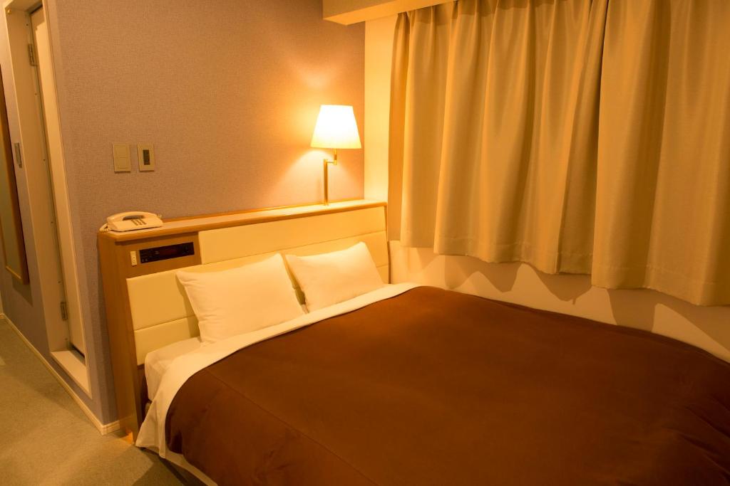 Postel nebo postele na pokoji v ubytování Nisshin Namba Inn