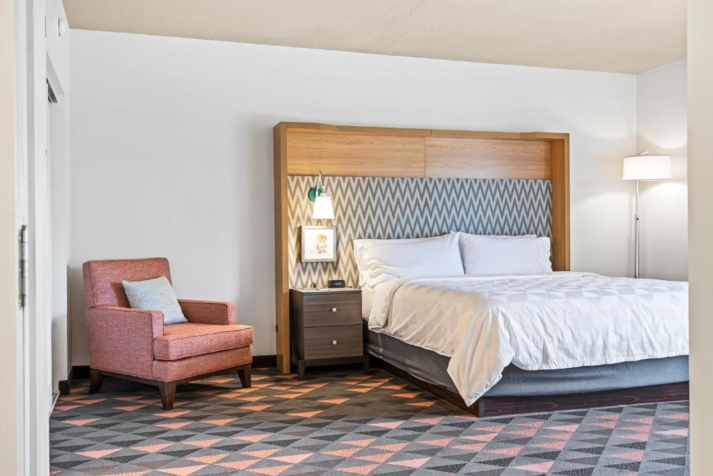 a bedroom with a large bed and a chair at Holiday Inn - St. Petersburg West by IHG in St Petersburg