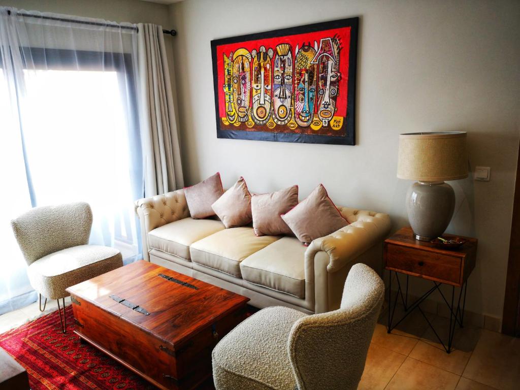 - un salon avec un canapé, des chaises et une table dans l'établissement Apartment E14, Forest View Apartments, à Kololi