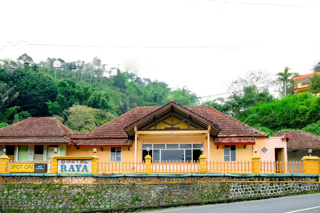 ein gelbes Haus am Straßenrand in der Unterkunft OYO Life 2638 Hotel Raya in Sarangan