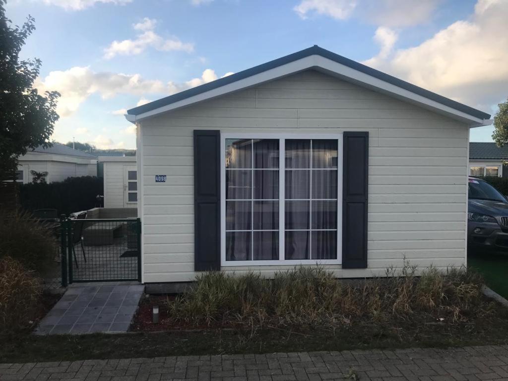 uma pequena casa branca com uma grande janela em Zeepark Haerendyke em De Haan