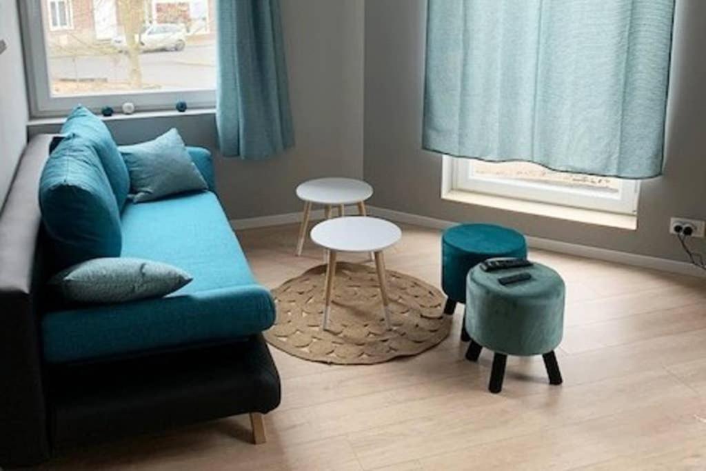 a living room with a blue couch and a table at Caudry : Bel appartement plein centre in Caudry