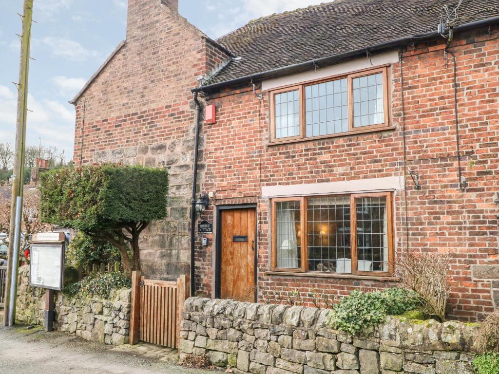 an old brick house with a stone wall at Middle Cottage in Stoke on Trent