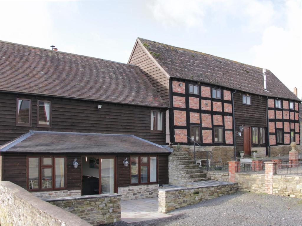 dois grandes edifícios de madeira com uma parede de pedra em Alders View Coach House em Craven Arms