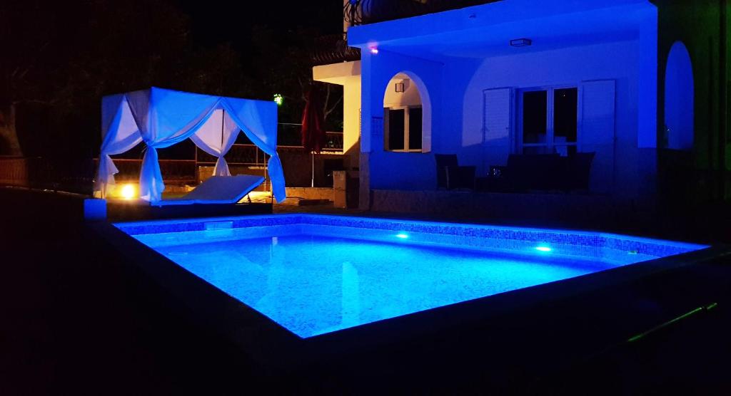 a swimming pool at night with blue lights at Villa Neptune Apartments in Vrboska
