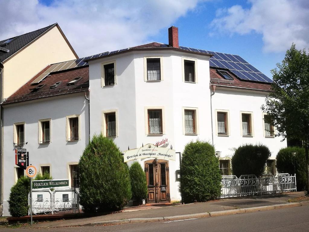 un edificio blanco con paneles solares en el techo en Pension & Gasthaus Nostalgie, en Chemnitz