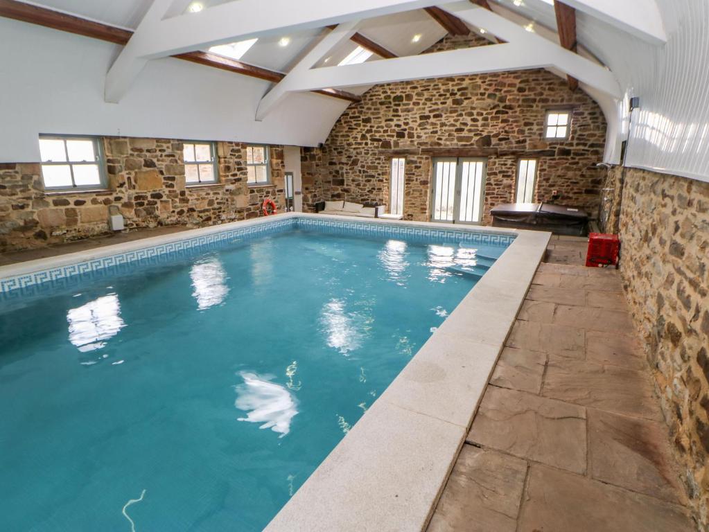 uma grande piscina interior com uma parede de pedra e tecto em Auckland Cottage em Bishop Auckland