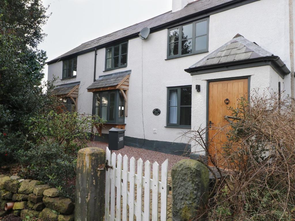 a white house with a wooden door and a fence at Holly Tree Cottage in Chester