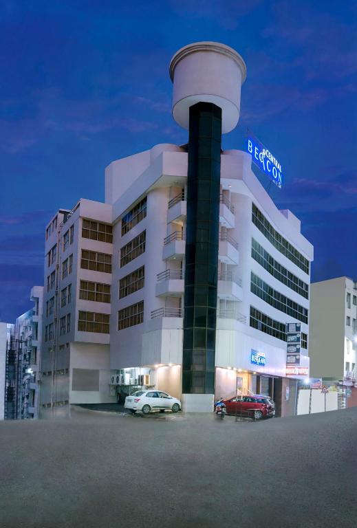 a large building with cars parked in front of it at Central Beacon Hotel in Surat