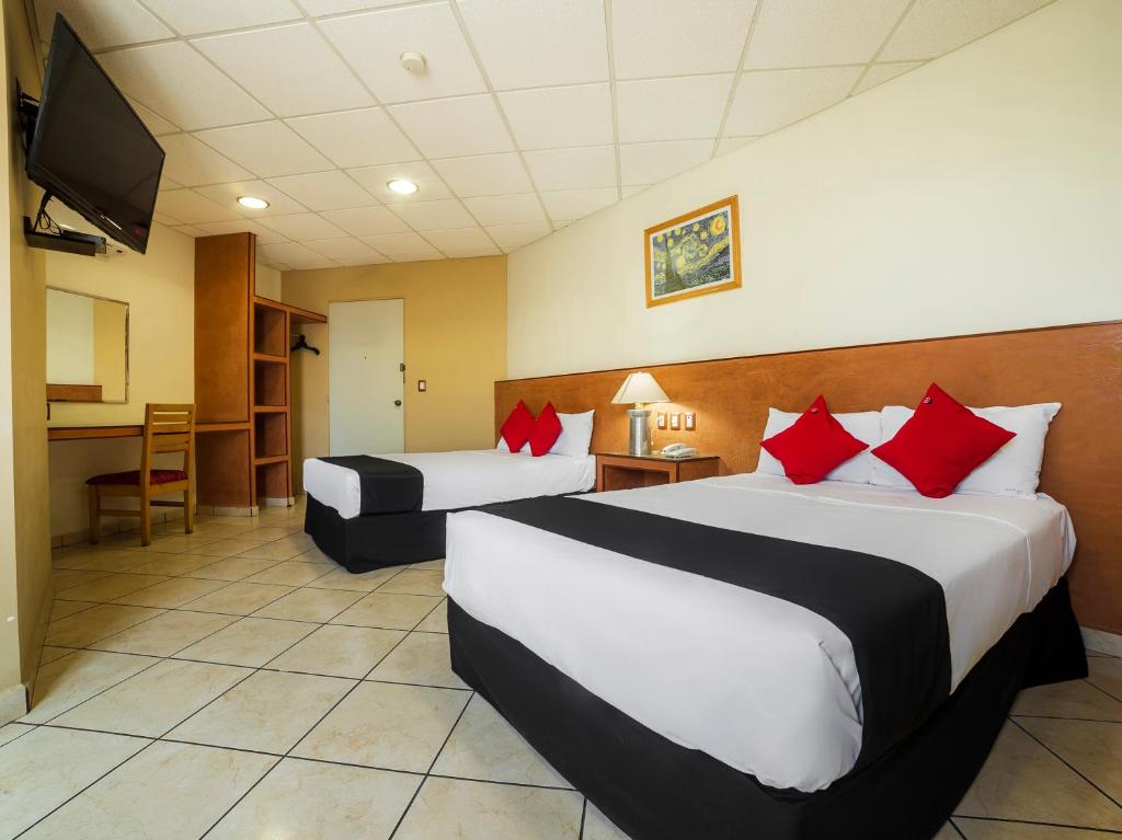 Habitación de hotel con 2 camas con almohadas rojas en Hotel Zadapi en Oaxaca de Juárez