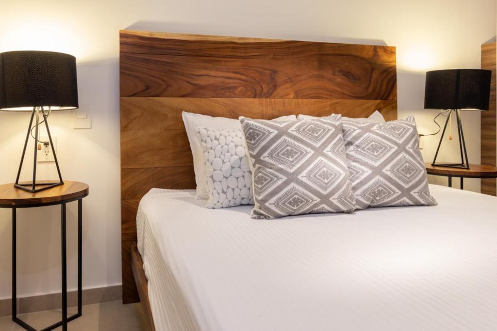 a bedroom with a bed with a wooden headboard and two lamps at Riva 202 Playa del Carmen Condo in Playa del Carmen