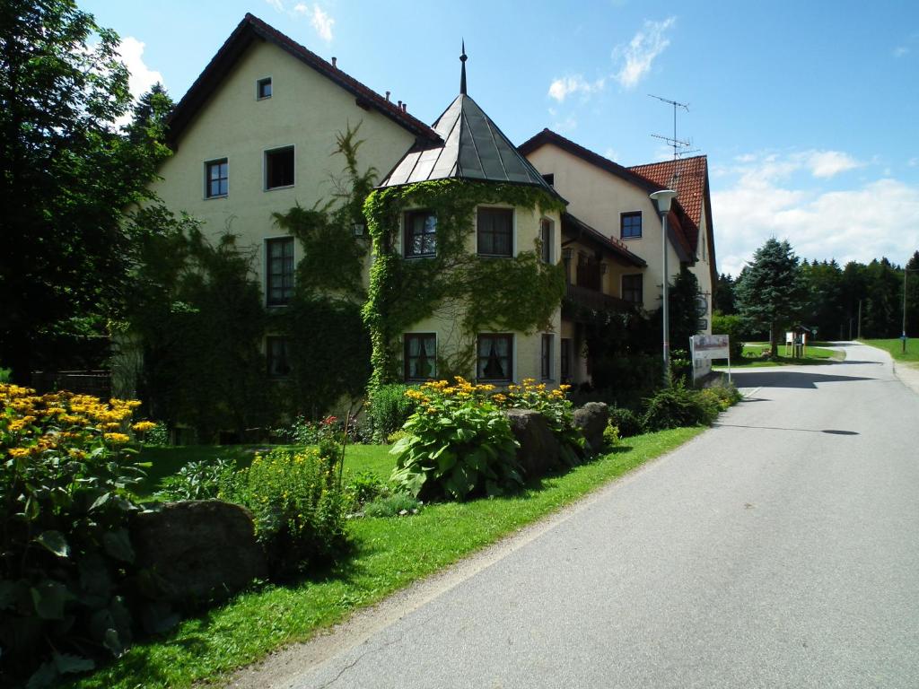 ein Haus am Straßenrand mit Blumen in der Unterkunft Waldgasthof - Hotel Schiederhof in Wiesenfelden