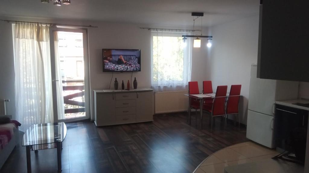 a living room with a table and red chairs at Apartament w Giżycku przy plaży in Giżycko