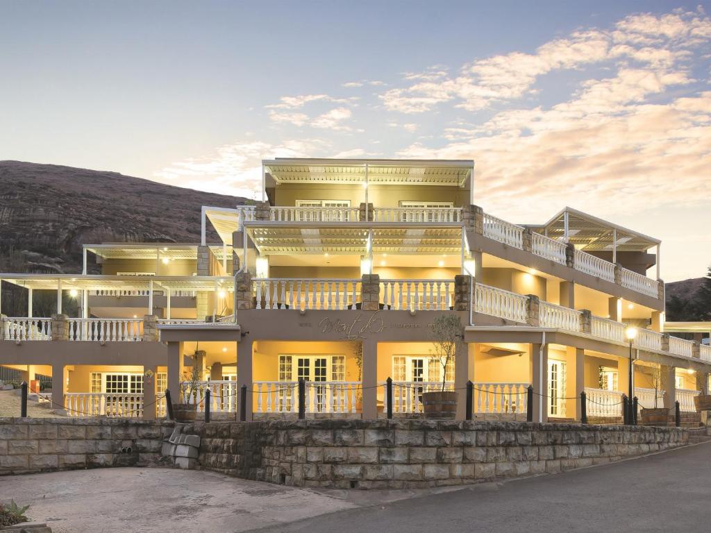 a large yellow building on the side of a hill at Mont d'Or Hotel Clarens in Clarens