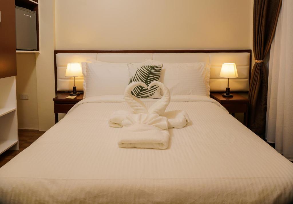 1 cama con toallas en forma de corazón en Amigos Dauin Hostel en Dauin