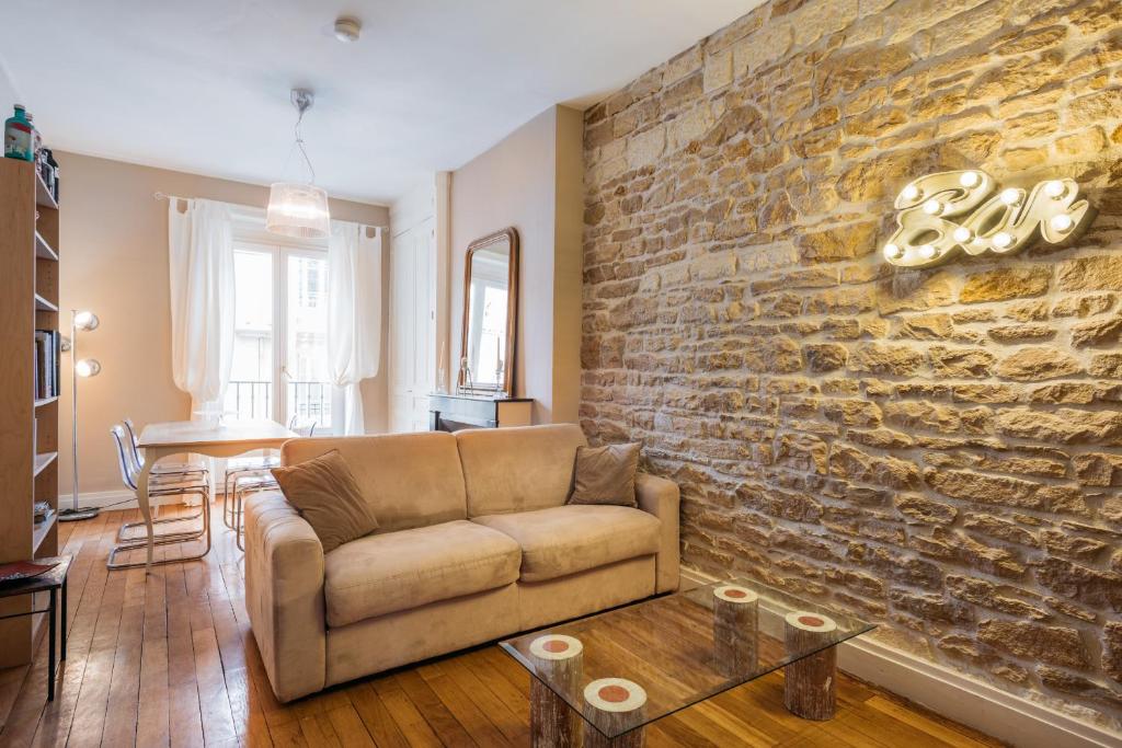 un salon avec un canapé et un mur en pierre dans l'établissement DIFY Universités - Bord du Rhône, à Lyon