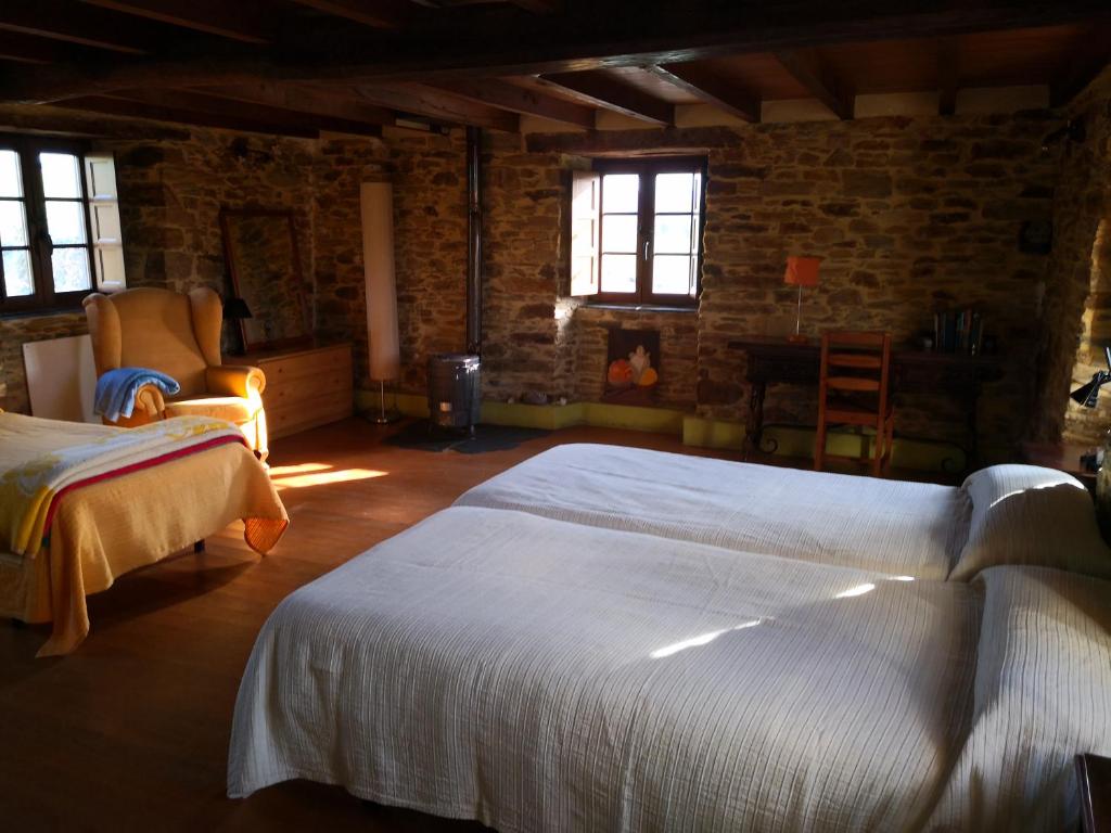 1 dormitorio con 2 camas, silla y ventanas en Casa a Pedra en Reiriz