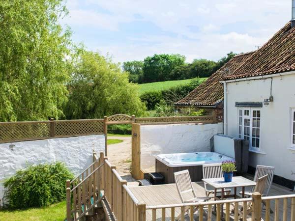 un patio trasero con bañera de hidromasaje y una casa en Derwent Cottage en Malton