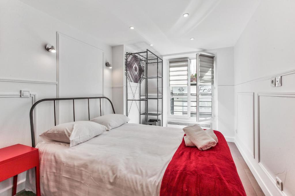 40-شقة باريس ايفل في باريس: غرفة نوم بيضاء مع سرير مع بطانية حمراء عليه