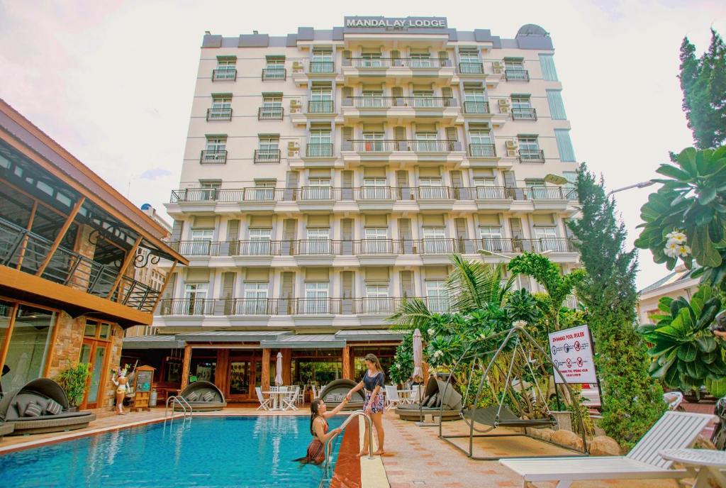 un hotel con piscina frente a un edificio en Mandalay Lodge Hotel en Mandalay