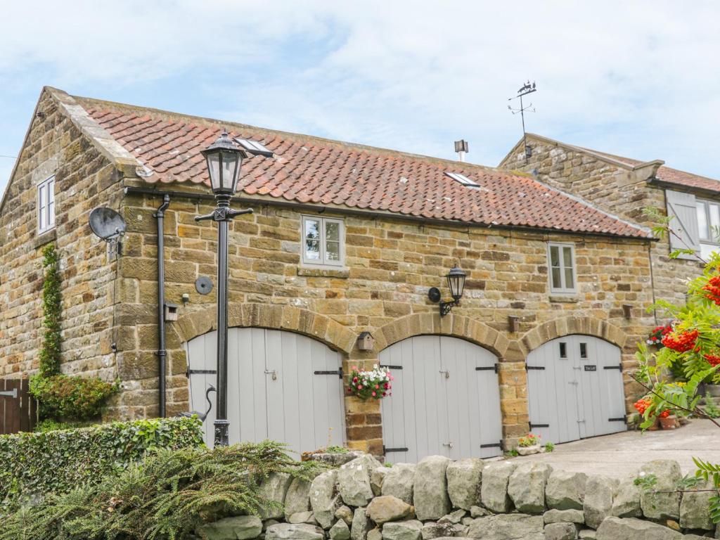 uma casa de pedra com duas portas de garagem brancas em The Loft em Scarborough